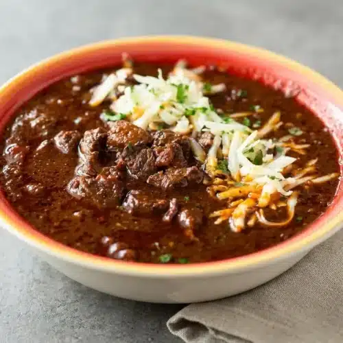 Brisket chili recipe served in a bowl with a rich mahogany sauce and tender beef cubes.