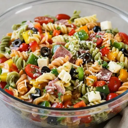 A colorful pasta salad recipe with glossy tricolor rotini, salami, mozzarella, and crisp diced bell peppers.