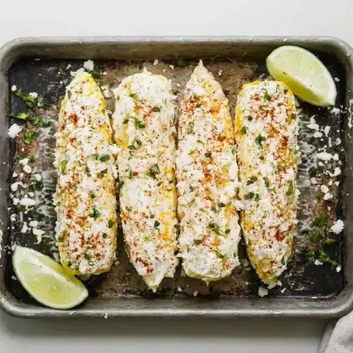 Perfectly charred ears of Mexican street corn prepared using this easy elote recipe, topped with creamy glaze and cotija.