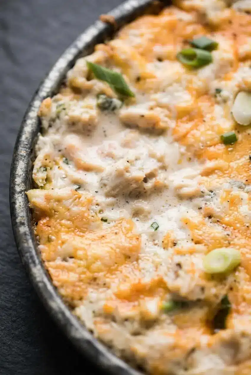 Close-up of bubbling baked crab dip showing tender lump crab meat, green onions, and melted cheese.