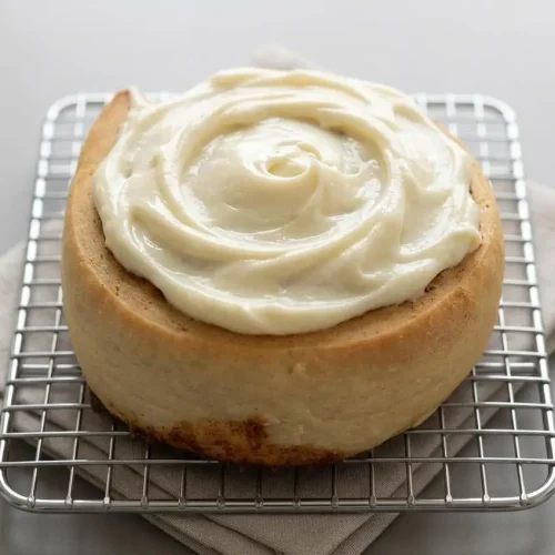 Cream cheese frosting for cinnamon rolls spread over freshly baked rolls with a glossy, satiny finish.