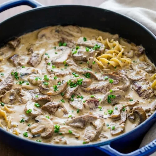 Tender beef stroganoff with seared steak strips and mushrooms in a glossy, creamy sauce served over egg noodles.