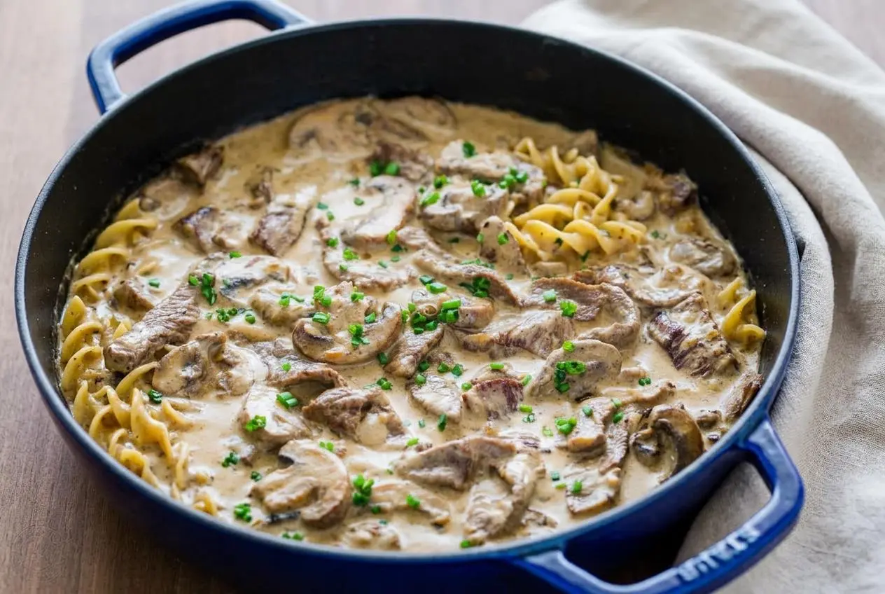 Tender beef stroganoff with seared steak strips and mushrooms in a glossy, creamy sauce served over egg noodles.