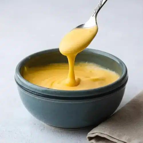 Rich and glossy cheddar cheese sauce recipe poured smoothly into a serving bowl.