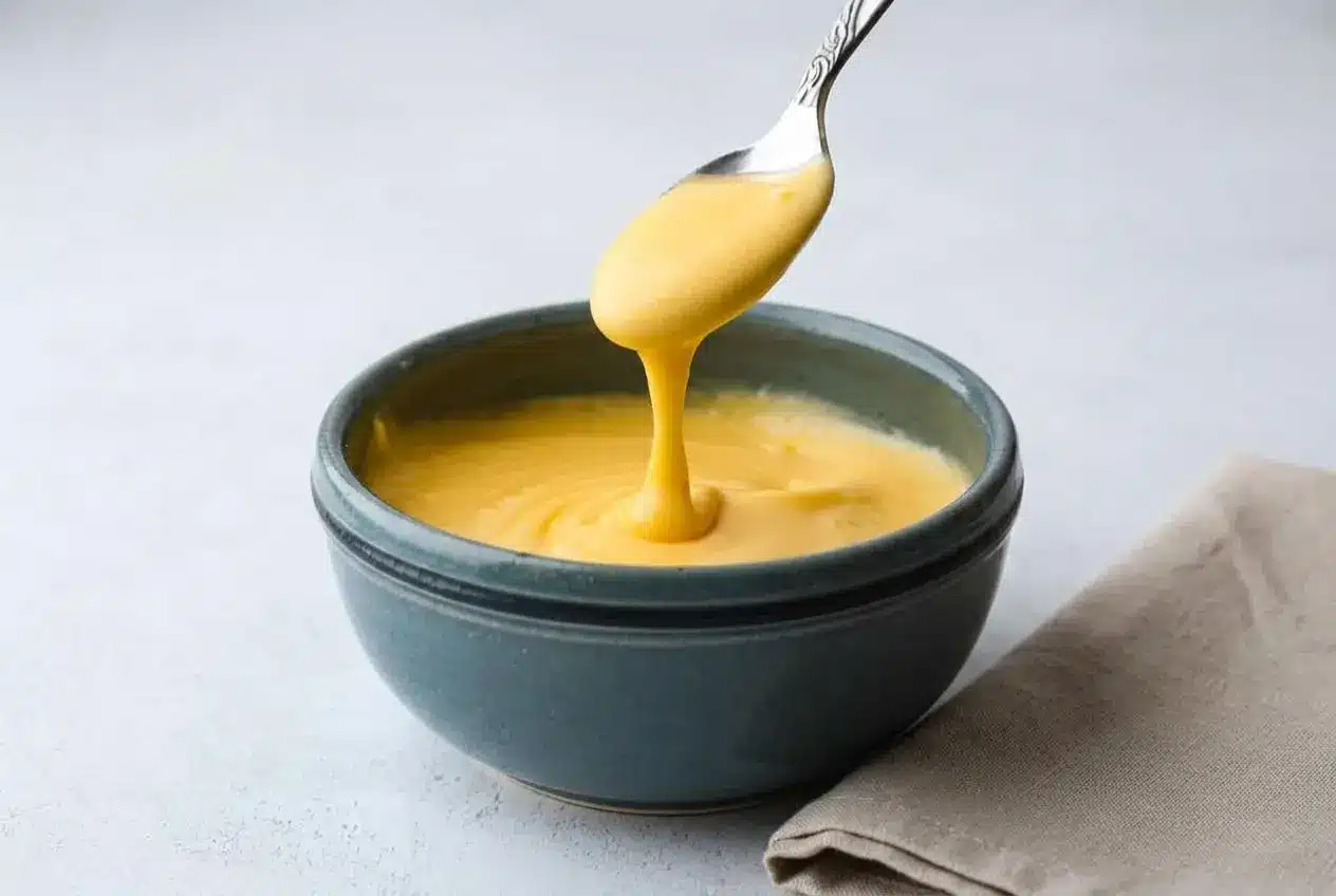 Rich and glossy cheddar cheese sauce recipe poured smoothly into a serving bowl.