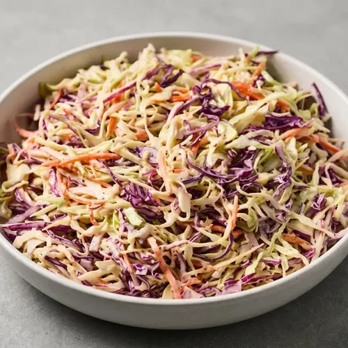 Creamy coleslaw recipe with crisp green and red cabbage, carrots, and glossy dressing.