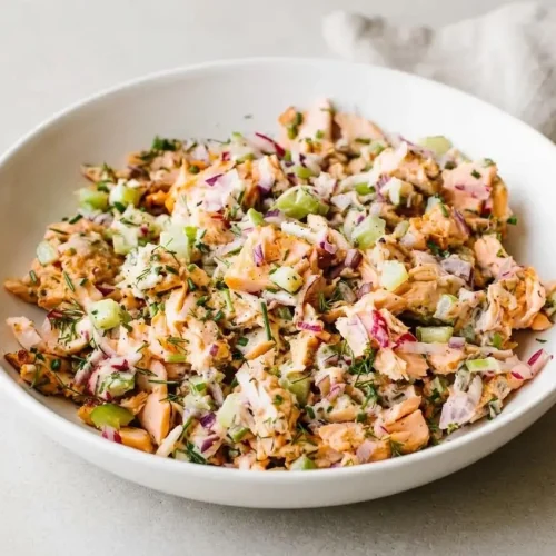 Creamy salmon salad with tender pink flakes, crisp celery, grated radishes, and fresh herbs.