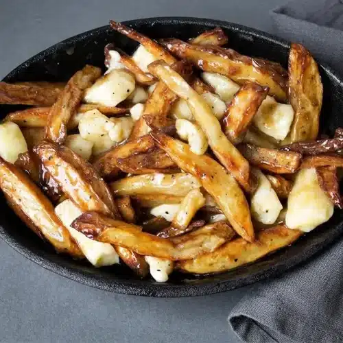 Crisp double-fried russet fries topped with white cheddar cheese curds and glossy brown poutine recipe gravy.