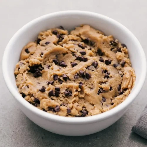 Scoop of creamy edible cookie dough recipe loaded with mini chocolate chips in a small bowl.