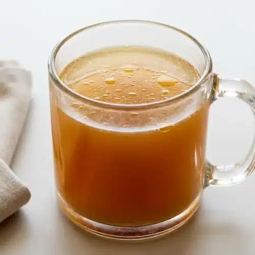Savory, golden-amber liquid in a clear jar from this easy bone broth recipe.