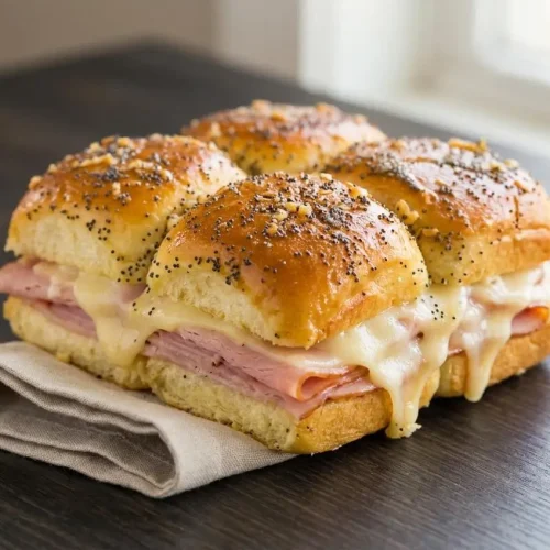 Baked ham and cheese sliders on sweet Hawaiian rolls with a glossy poppy seed glaze and melted Swiss cheese.