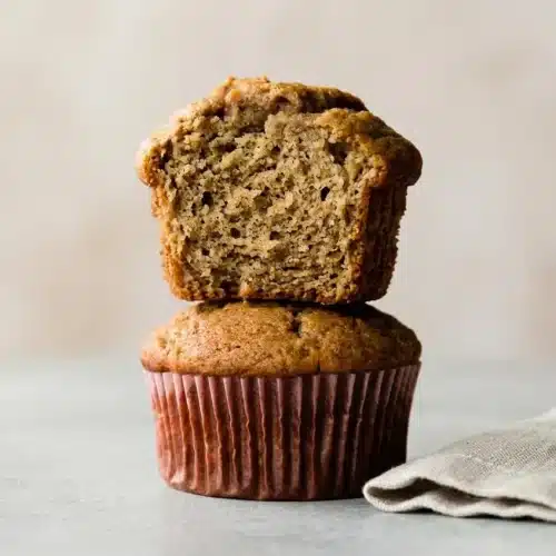 Golden brown banana muffins with tall bakery style domed tops resting fresh from the oven