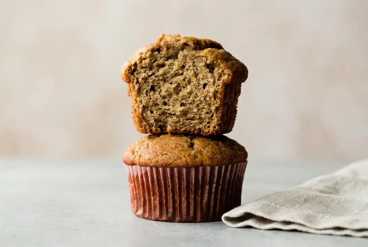 Golden brown banana muffins with tall bakery style domed tops resting fresh from the oven