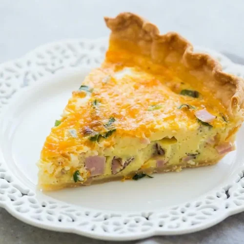 Golden baked quiche recipe slice with a flaky crust and rich ham and cheddar custard filling.