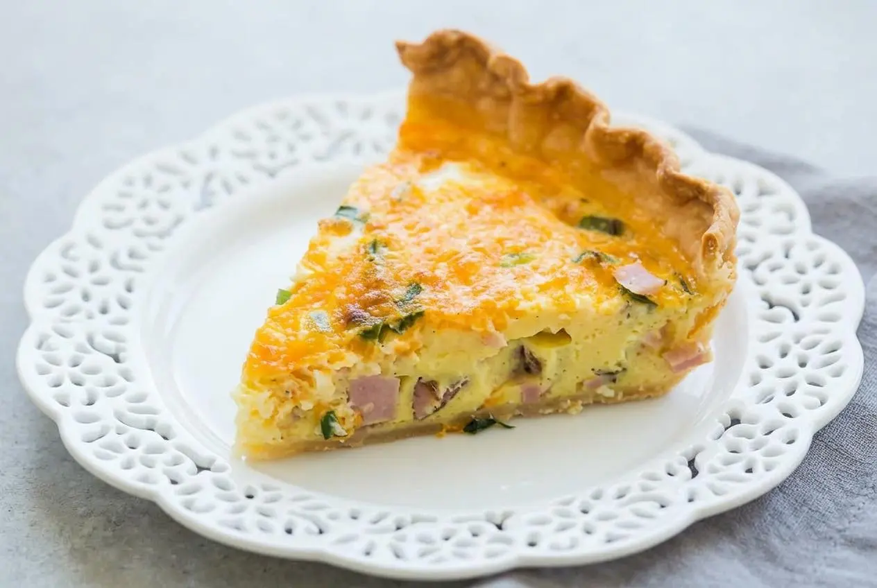 Golden baked quiche recipe slice with a flaky crust and rich ham and cheddar custard filling.