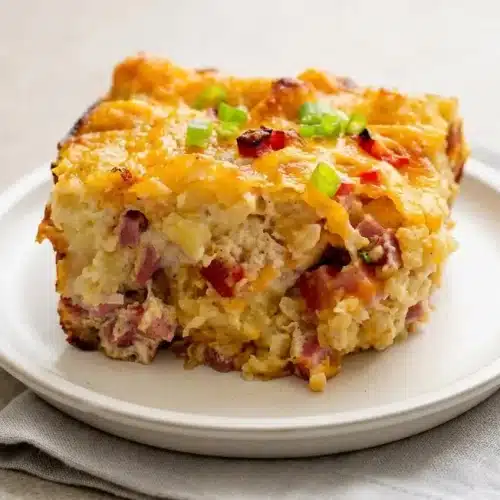 Golden baked tater tot breakfast casserole in a baking dish with melted cheddar cheese and savory ham.