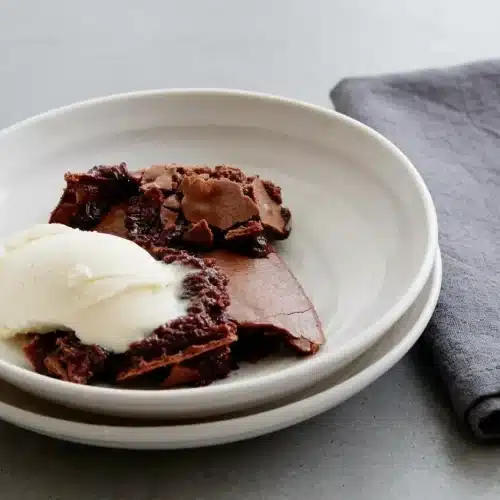 Baked Ina Garten brownie pudding in an oval dish with a crisp cocoa crust and molten chocolate center.