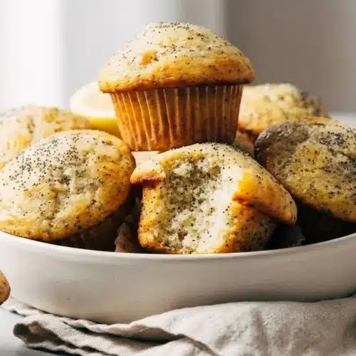 Freshly baked lemon poppy seed muffins with tall domed tops and a light glossy citrus glaze.
