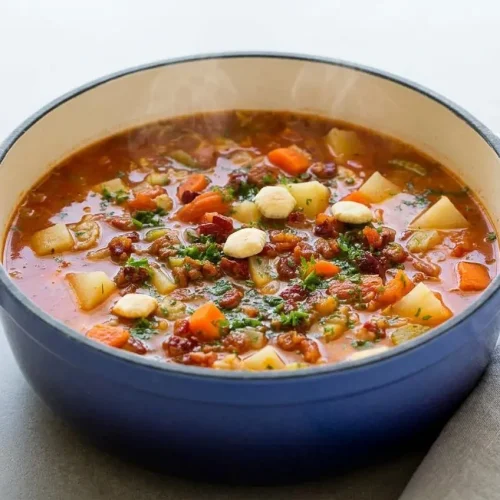 Manhattan clam chowder in a rustic bowl with savory tomato broth, tender potatoes, and crispy bacon.