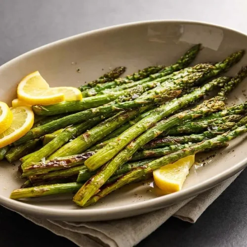 Tender roasted asparagus spears with crispy charred tips on a baking sheet.