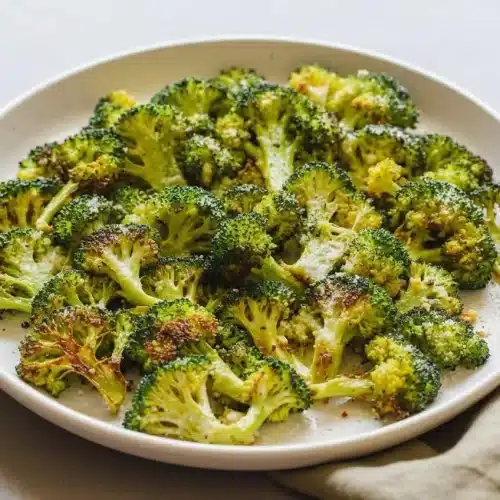 Perfectly roasted broccoli florets with caramelized golden edges in a serving bowl, showcasing tender stems.