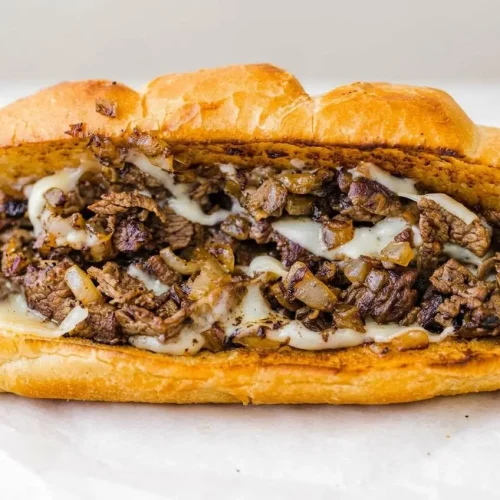 Philly cheesesteak recipe with juicy shaved ribeye, caramelized onions, and melted provolone on a toasted roll