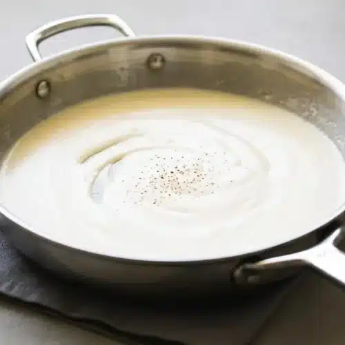 Silky bechamel sauce poured into a ceramic serving dish, highlighting its creamy and smooth texture.