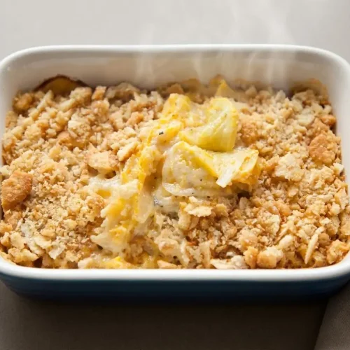 A baked yellow squash casserole recipe featuring a golden, bubbly cheese edge and a crisp cracker topping.