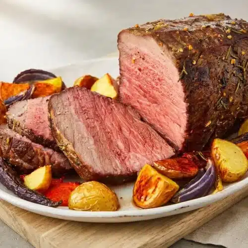 Tender garlic herb crusted roast beef sliced to show a juicy, rosy pink medium-rare center.