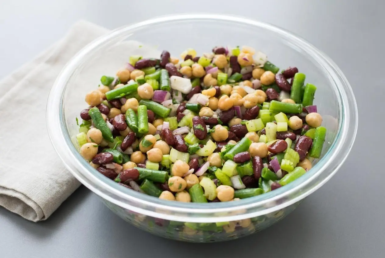A vibrant three bean salad recipe featuring dark kidney beans, chickpeas, and green beans with a glossy dressing.