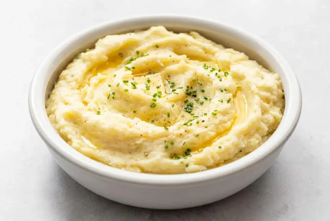 Creamy and fluffy Yukon Gold mashed potatoes in a bowl, topped with melted butter and chopped chives.