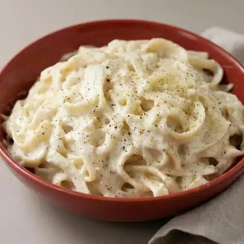 Velvety alfredo sauce with cream cheese and black pepper spooned over fettuccine with a glossy finish.