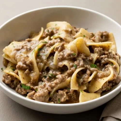 Comforting bowl of beef and noodles recipe featuring tender egg noodles in glossy brown gravy.