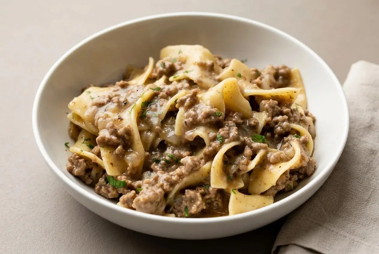 Comforting bowl of beef and noodles recipe featuring tender egg noodles in glossy brown gravy.