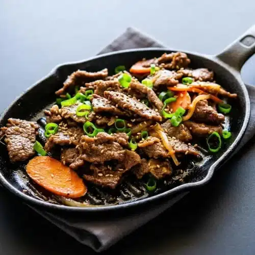 Tender beef bulgogi recipe with a glossy sweet-savory glaze, caramelized edges, and toasted sesame seeds.