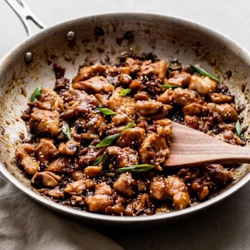 Glazed bourbon chicken recipe skillet bites with a glossy caramelized sauce, sesame seeds, and green onions.
