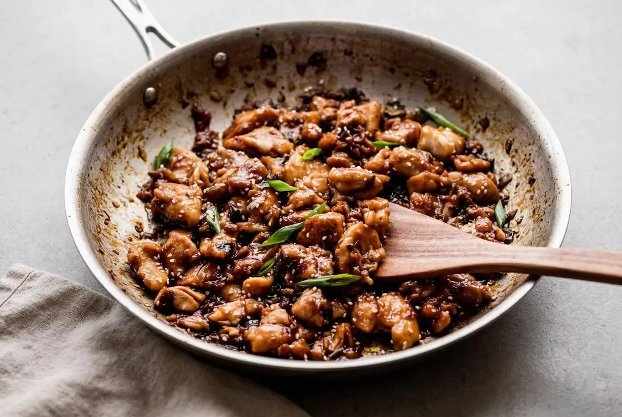 Glazed bourbon chicken recipe skillet bites with a glossy caramelized sauce, sesame seeds, and green onions.