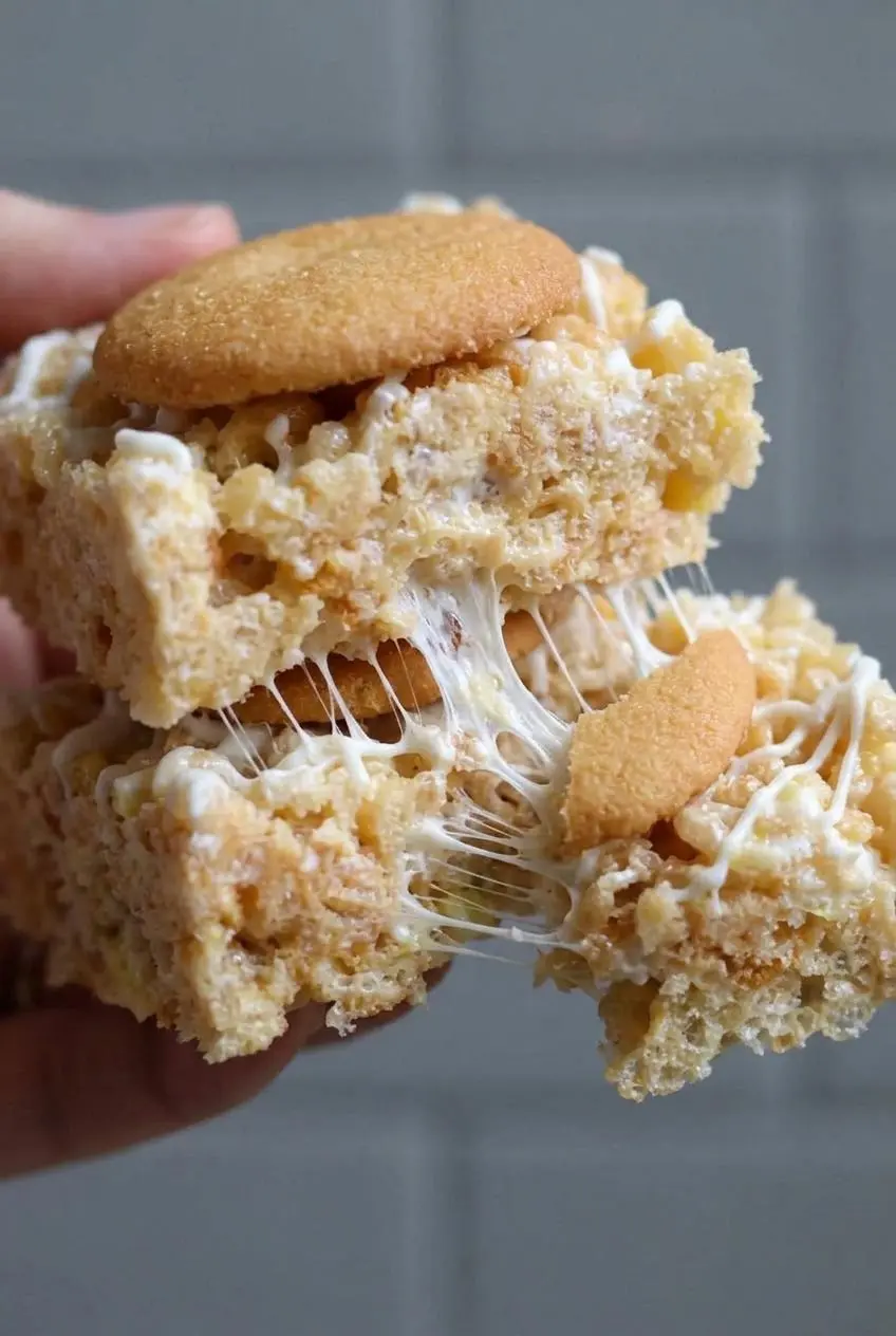 Close-up of a pulled-apart banana pudding cereal treat showing gooey marshmallow strings.