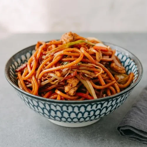 Tender chicken lo mein tossed with egg noodles, shredded cabbage, carrots, and a glossy dark soy glaze.