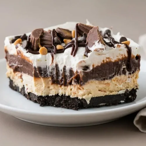 Chocolate peanut butter lasagna with fluffy mousse, rich pudding, and a glossy chocolate drizzle.