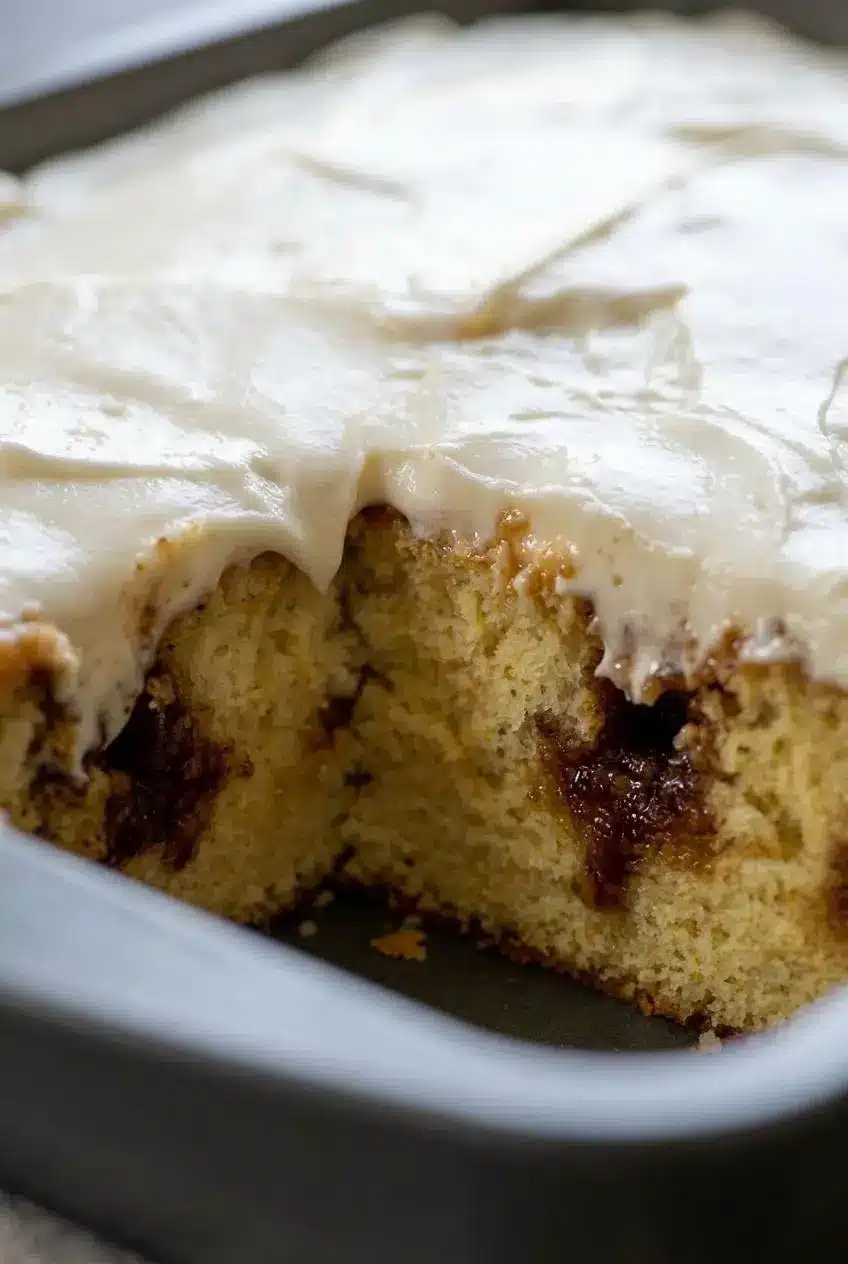 Cross section of poke cake showing deep cinnamon filling soaking through the tender vanilla crumb.