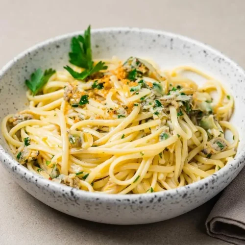 Bowl of glossy clam linguine tossed with tender baby clams, sliced garlic, and fresh Italian parsley.