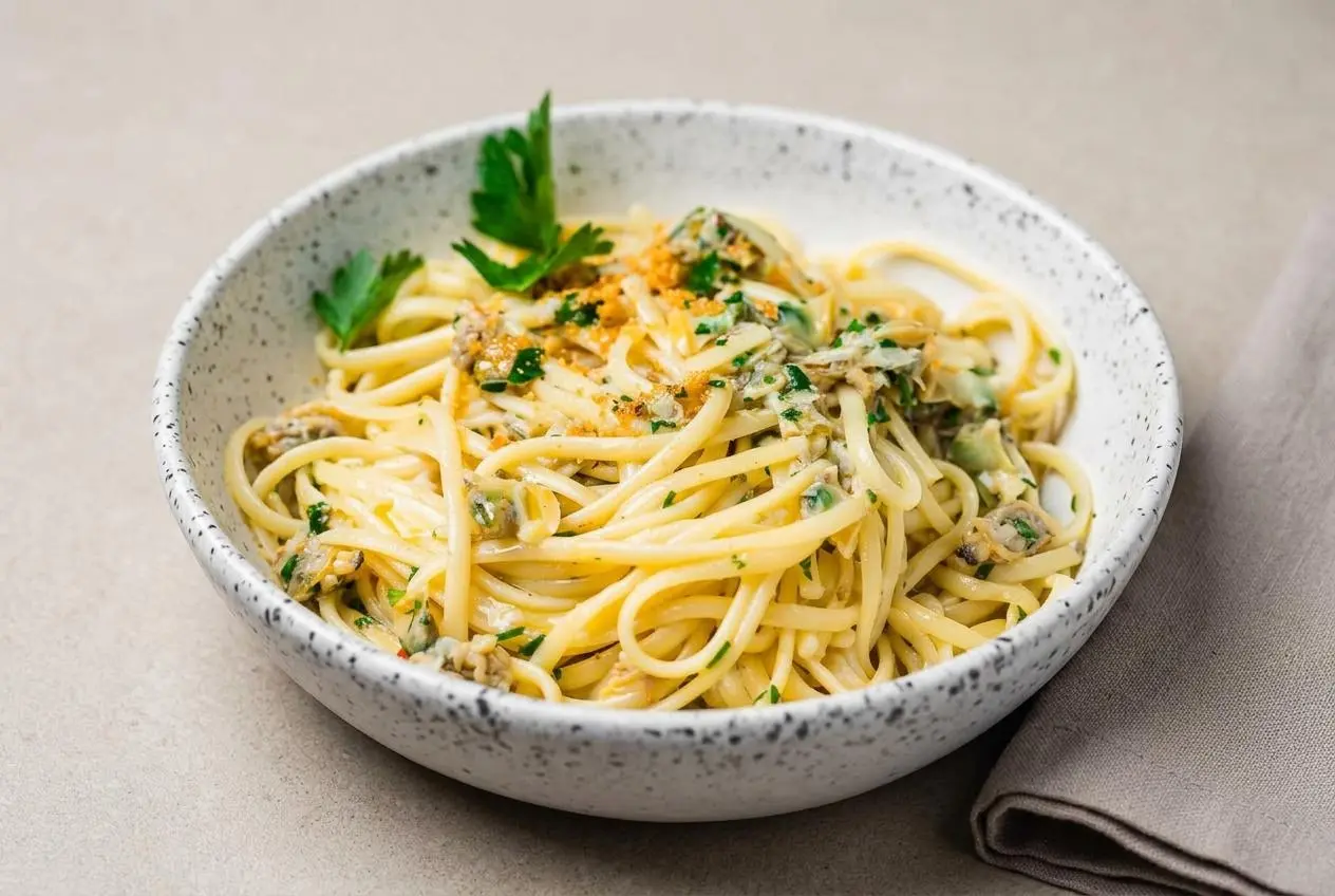 Bowl of glossy clam linguine tossed with tender baby clams, sliced garlic, and fresh Italian parsley.