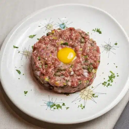 Finely hand-diced beef tartare tossed in a glossy egg yolk dressing with capers and fresh parsley.