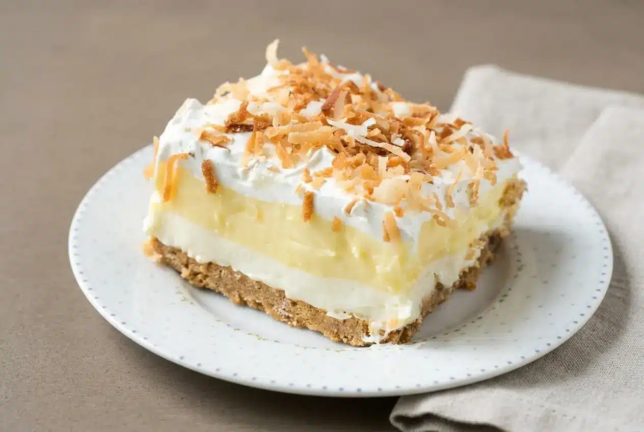Chilled coconut cream lush square with creamy pudding layers and toasted coconut flakes on top.