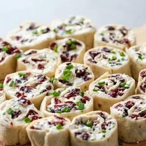 Cranberry feta pinwheels tightly rolled in tortillas showcasing creamy cheese and sweet ruby-red cranberries.