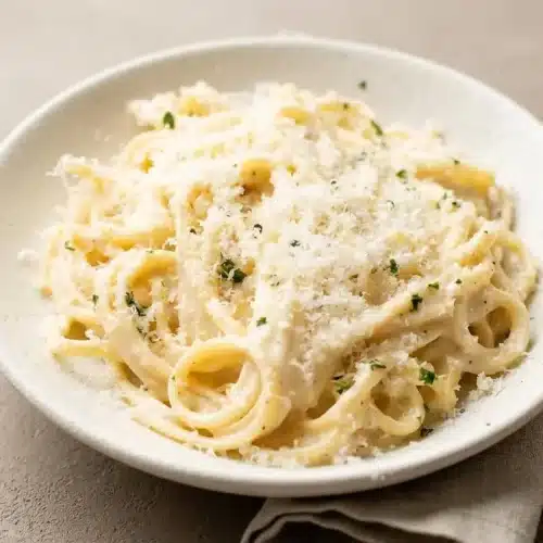 Creamy Garlic Pasta with a silky, glossy parmesan sauce clinging to linguine strands topped with fresh parsley.