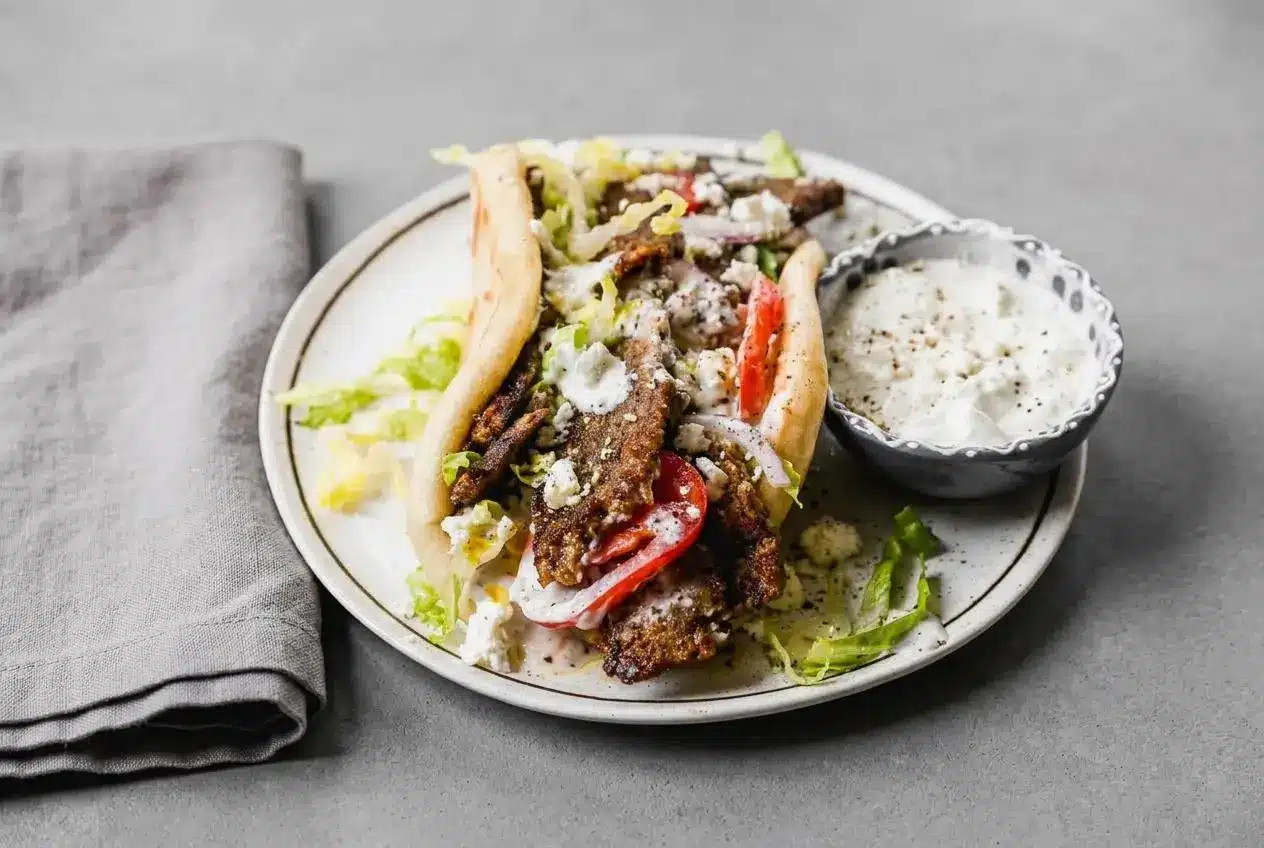 Lamb gyros tucked into warm pita bread with crisp seared meat strips, cool tzatziki, and sliced tomatoes.