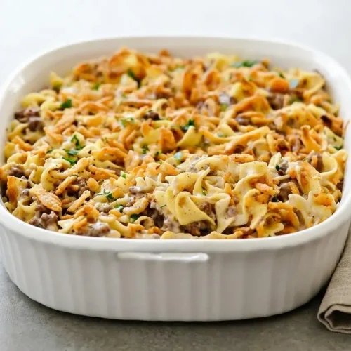 French onion beef casserole topped with crispy fried onions in a ceramic baking dish.