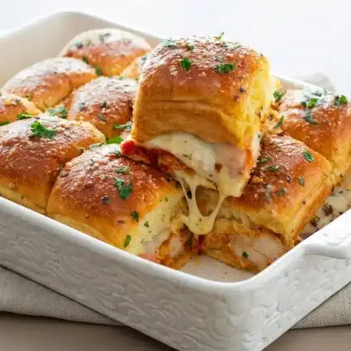 Baked chicken parmesan sliders with golden garlic butter tops, melted mozzarella, and marinara.
